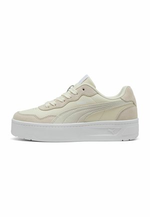 Cream-colored sneakers with a smooth and suede texture, featuring a thick white sole and subtle branding on the side, with lace closure.