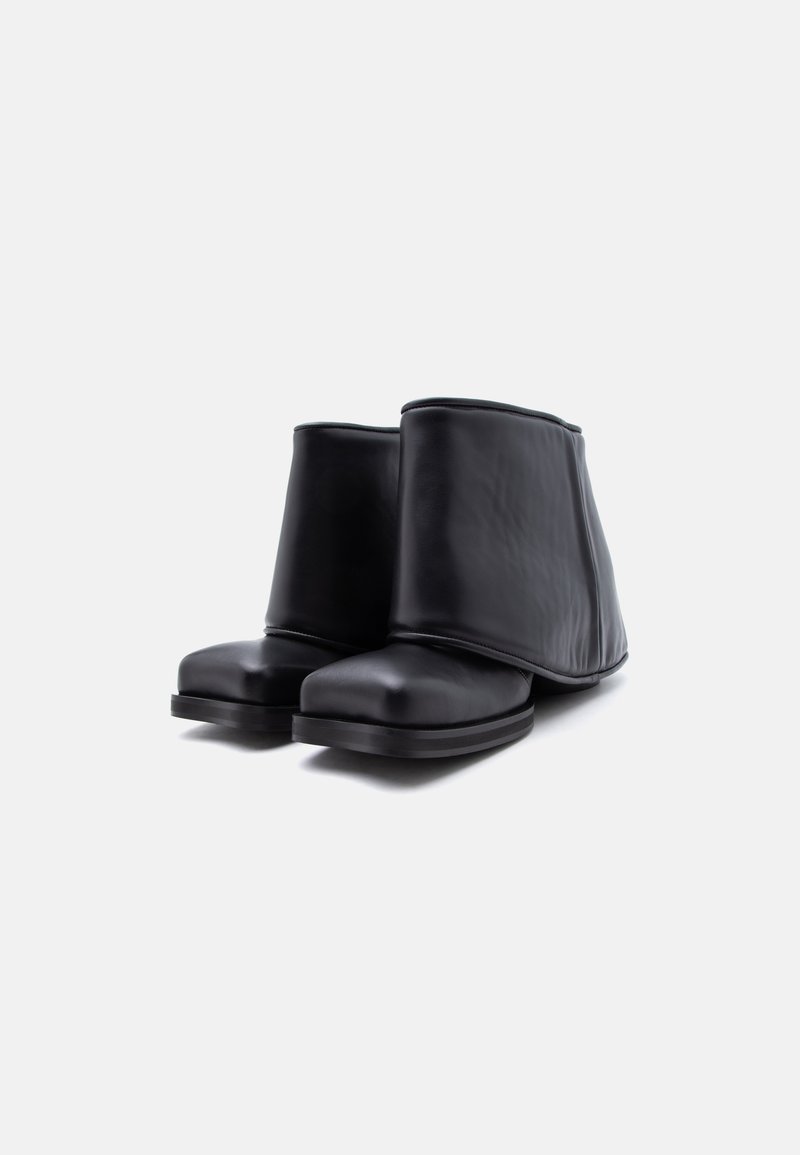 Black leather square-toe ankle boots with wide, soft folded-over upper flaps and flat soles on a white background.
