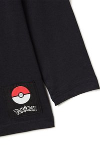 Zwarte katoenen t-shirtmouw met een vierkante patch met een rood-wit Poké Ball ontwerp en de tekst "Pokémon" in witte letters eronder.