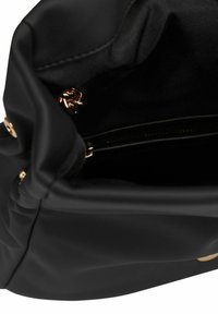 Borsa a tracolla in pelle nera aperta per mostrare l'interno foderato in tessuto e un piccolo dettaglio in catena dorata vicino alla tasca con cerniera.