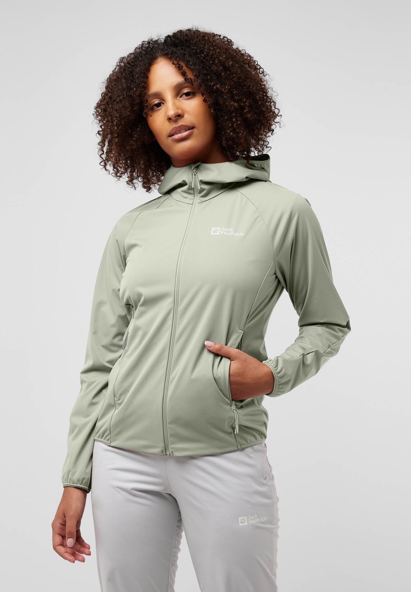Veste légère de couleur vert clair, avec capuche, fermeture éclair, deux poches latérales et détail de logo. Texture lisse et design ajusté.