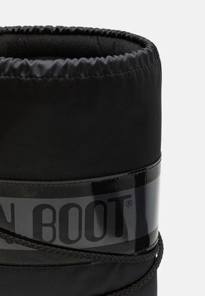 Botte noire isolée avec un col rond rembourré, une bande brillante autour de la section médiane et des détails en lacets texturés. Le tissu semble élégant et durable.