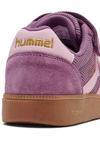Fioletowy zamszowy i siateczkowy sneaker z różowym wzmacniaczem na pięcie, złotym logo "hummel" oraz gumową podeszwą z teksturowanymi detalami.