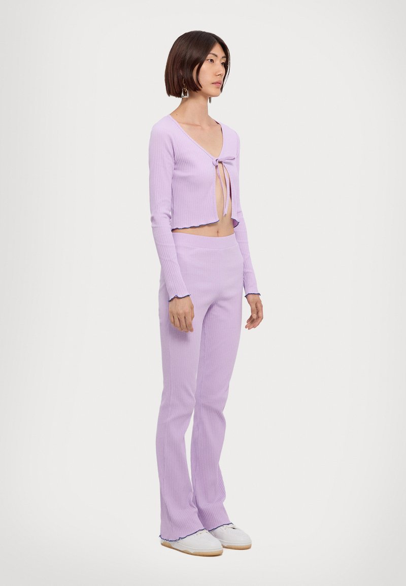 Lilac ribbed two-piece set featuring a cropped top with a front tie and flared pants with scalloped hems. Material has a soft texture.