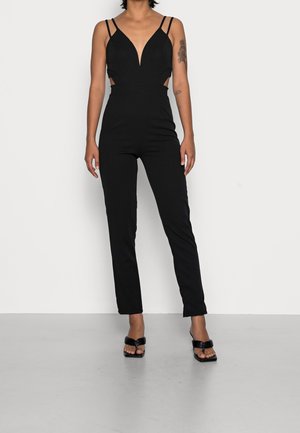 Black jumpsuit with a plunging V-neck, spaghetti straps, and side cutouts. Fitted style with straight legs and minimalistic design.