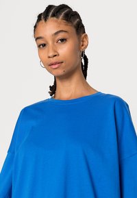 Blauw oversized T-shirt van katoen, met een ronde hals en korte mouwen. Gladde textuur met een ontspannen pasvorm en zonder zichtbare patronen of accenten.