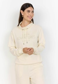 Kremowa bluza z kapturem ze sznurkami, z napisem "NIECH NOWE PRZYGODY SIĘ ZACZNĄ" w jasnobrązowym kolorze. Miękka tkanina i luźny krój.