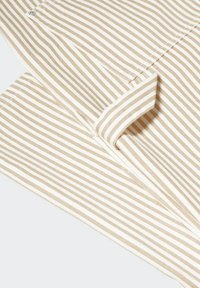 Béžová a bílá pruhovaná látka s hladkou texturou; má sklóňené okraje a viditelné švy; obsahuje kovové patentky.