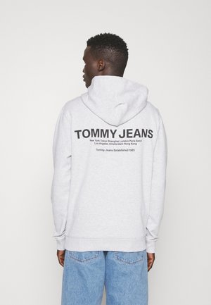 Grijze sweatshirt met capuchon. Bevat het "TOMMY JEANS" logo op de achterkant in het zwart, samen met stadsnamen en oprichtingsdatum. Casual fit.