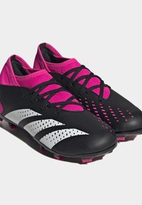 Schwarz-rosa Fußballschuhe mit einer strukturierten Oberfläche; ausgestattet mit drei weißen Streifen, durchbrochenen Mustern und schwarzen Schnürsenkeln.
