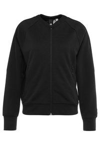 Chaqueta negra con cremallera hecha de un tejido suave. Presenta un cuello redondo, mangas raglán y dos bolsillos laterales con cremalleras, de textura lisa.