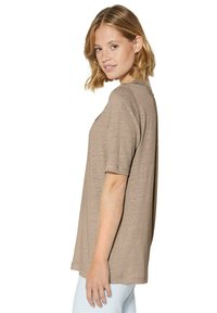 Hellbraunes Kurzarm-T-Shirt mit lockerer Passform und einem strukturierten Rückendetail, kombiniert mit hellen gemusterten Leggings.