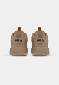 Brune idrettssko med en jevn tekstur, med en trekktab ved hælen og Fila-logo. Rund form, polstret mellomsåle og gummisåle.