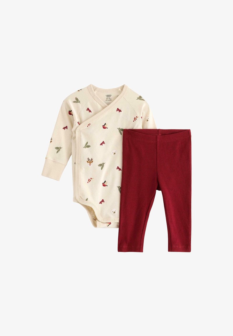 Bavlněný kojenecký overal v krémové barvě s různými potisky malých zvířat a rostlin, v kombinaci s červenými žebrovanými legínami, které jsou navrženy pro pohodlí.