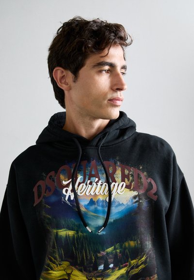 Felpa con cappuccio nera caratterizzata da una grafica colorata di un paesaggio naturale con montagne e alberi, dettagliata con lacci e una stampa che recita "DSQUARED2 Heritage."