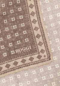 Tissu à motifs marron et crème présentant des motifs carrés et en losange, avec l'étiquette "BOGGI" visible sur le bord. Fini texturé.