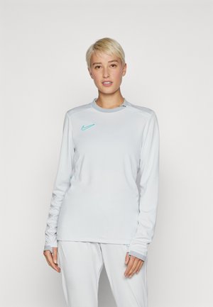 Maglietta sportiva a maniche lunghe di un grigio chiaro con colletto tondo e logo Nike turchese, caratterizzata da una texture liscia e una vestibilità aderente.
