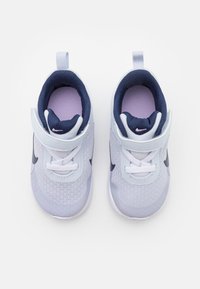 Svijetloplave i tamnoplave tenisice s mrežastim gornjim dijelom, podstavljenim ovratnikom i podesivim remenom. Imaju kontrastni swoosh logo i vezice.
