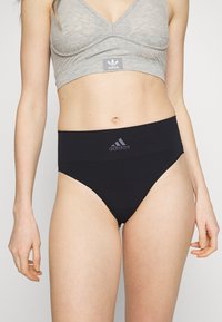 Fekete, magas derekú bugyi, puha anyagból készült, széles derékkal, elöl diszkrét Adidas logóval.