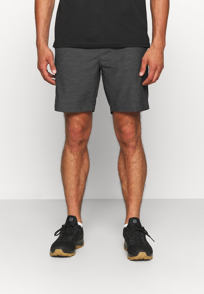 Dunkelgraue Herrenshorts aus leichtem Material mit glatter Textur, kombiniert mit schwarzen Sportschuhen mit heller Sohle.