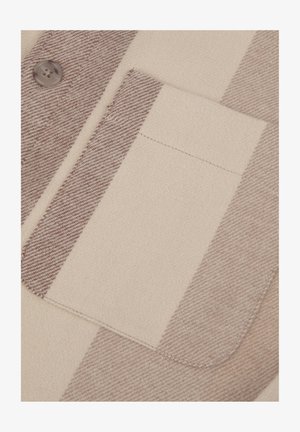 Tela a rayas beige y marrón con una textura suave, que presenta un pequeño bolsillo en el pecho y un detalle de botón redondo.