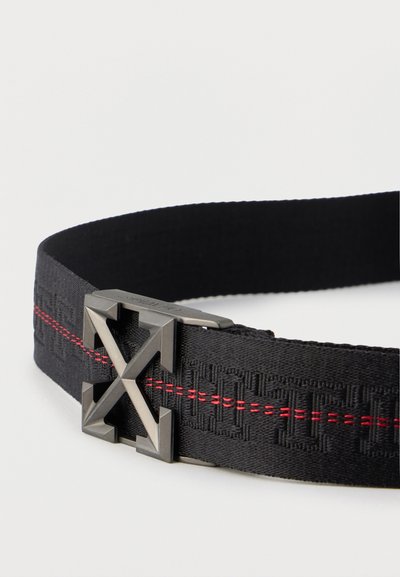 Μαύρη υφασμάτινη ζώνη με ανάγλυφο σχέδιο και κόκκινη ραφή, με αγκράφα από γκάντ μέταλλο σε σχήμα διασταυρούμενων βελών.