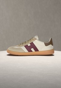 Μπεζ sneaker χαμηλού ύψους με σόλα από καουτσούκ, μπεζ δερμάτινη μύτη, καφέ τακούνι και μεγάλο μπορντό γράμμα H στο πλάι.