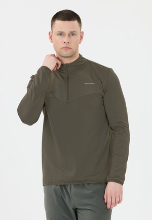 Mörkgrön skjorta med långa ärmar, hög krage och fjärdedels dragkedja. Den texturerade tyget har en sydd design vid övre bröstet.