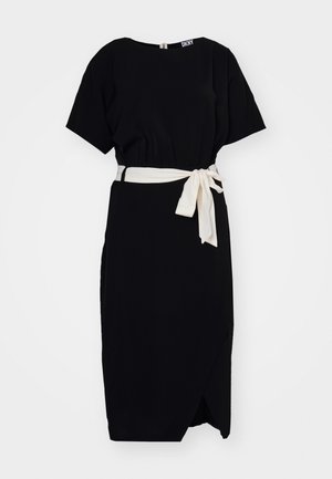 Vestido preto feito de tecido leve, com mangas curtas, uma cintura cingida com um laço creme e um detalhe de saia envolvente.