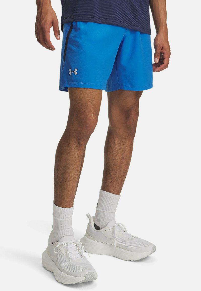 Blå sportshorts med en kontrasterande svart rand och silverlogotyp. Bärs med vita sneakers och vita ribbade strumpor.