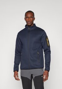 Námornícky zip-up kabát z textúrovanej tkaniny, s vysokým golierom, žltými akcentmi a zipsovou kapsou na ľavom rukáve.