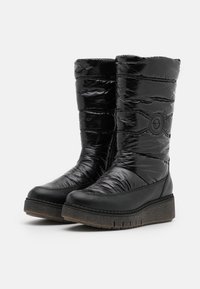 Schwarze, isolierte, knielange Stiefel aus glänzendem Puffer-Material, mit strukturierter Sohle und kreisförmigem Logo-Akzent an der Seite.