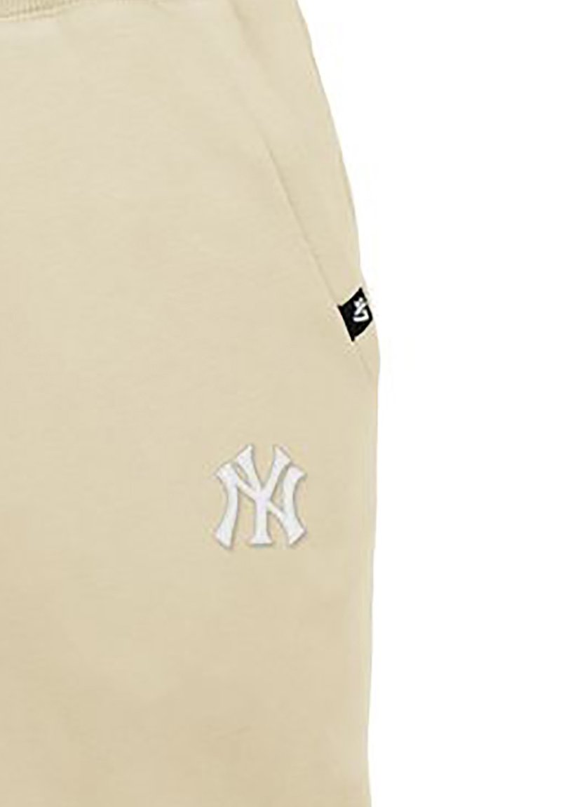 Beige sweatpants made of soft cotton, featuring an embroidered NY logo in white. Includes a small black tag on the side seam.