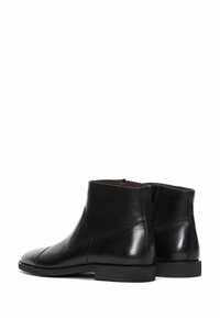 Botas de cuero negras hasta el tobillo con un acabado suave, punta redondeada y detalle de cremallera lateral. Presentan costuras mínimas y una suela de goma plana.