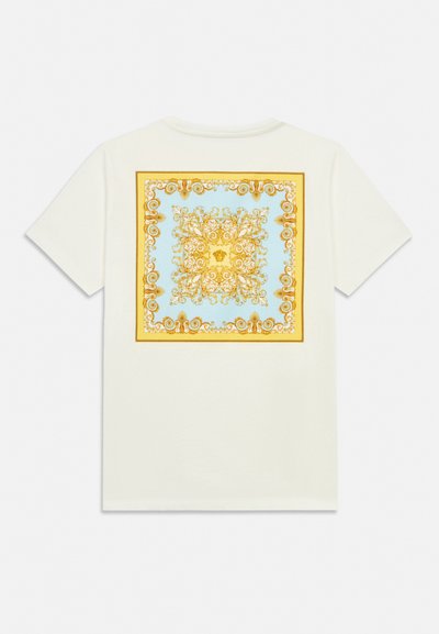 Balta īsroku T-krekls ar lielu kvadrātveida greznu zelta un zilas baroka rakstu, kas novietots muguras centrā.