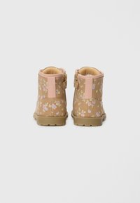 Bottines marron avec un imprimé floral rose et vert. Matériau texturé, fermeture éclair sur le côté et accents roses au col et au talon.