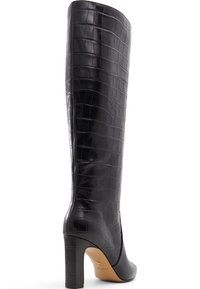 Bota negra de cuero sintético imitación cocodrilo hasta la rodilla, con punta afilada y un tacón grueso y alto. Textura suave con un acabado brillante.