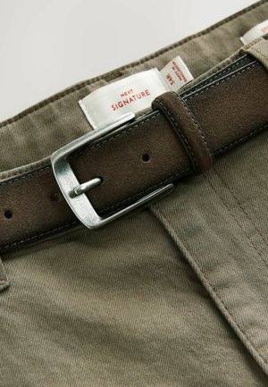 Khaki bomuldsbukser med et brunt ruskindsbælte, der har en metallic sølvspænde, synlige mærkater og subtile teksturdetaljer.