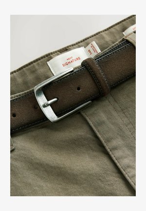 Khaki-cotton housut ruskealla mokkabeltillä, jossa on metallinen hopea solki, näkyvät hintalaput ja hienovaraisia tekstuuritietoja.