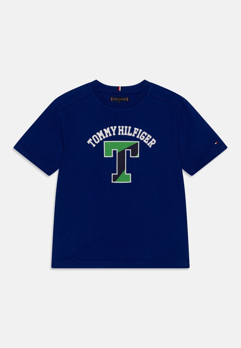Marineblaues, kurzärmeliges T-Shirt mit dem Schriftzug „Tommy Hilfiger“ und einem großen grünen und schwarzen "T"-Logo auf der Vorderseite.