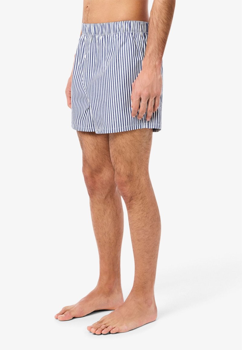 Blue and white striped swim shorts with an elastic waistband, knee-length cut, and no visible hardware or patterns aside from stripes.