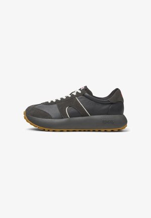 Sneaker atletica grigia con una combinazione di pelle e suede, suola di gomma spessa, lacci bianchi e un branding discreto sul tallone.