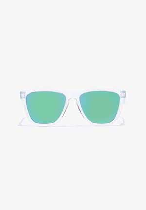 Saulesbrilles ar caurspīdīgām plastmasas ap Frames un zaļiem gradienta objektīviem, ar retro formu un stūrainām malām. Nav redzamas zīmola pazīmes.