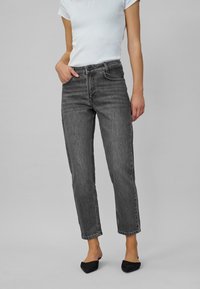 Gray denim jeans with a straight-leg cut and five-pocket design. Features a high waist and subtle fading. Paired with a fitted white T-shirt.