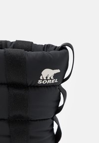 Black puffer bag with stitched design and black straps. Features a white Sorel logo on the side. Material appears smooth and padded.