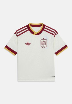 Hvit fotballdrakt med kastanjebrun og gull kanting, kastanjebrunt Adidas-logo på høyre bryst og Spanias landslagsmerke på venstre bryst.