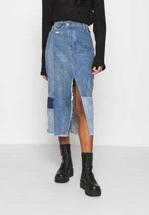 Jupe midi en denim avec un design en patchwork dans des tons de bleu clair et foncé, ourlet effiloché et fente à l'avant. Assortie à des bottes de combat noires.