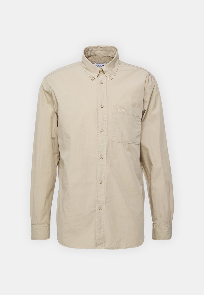 Beige langemouw overhemd met knoopsluiting, een puntkraag en een borstzak met een klein geborduurd logo.