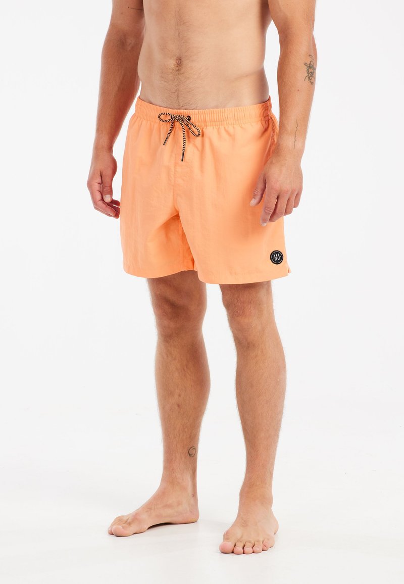 Shorts de bain pêche avec une taille élastique, cordon noir, et poches latérales avec fente. Patch logo noir sur la cuisse gauche.