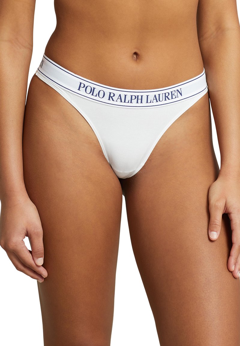 Balts kokvilnas šortītes ar plašu jostasvīru, uz kuras ir uzraksts "POLO RALPH LAUREN" tumši zilā krāsā. Gluda tekstūra ar minimālas seguma dizainu.